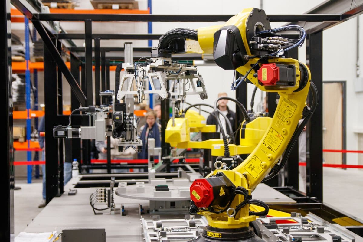 Industrial robot arm operating autonomously on a smart manufacturing facility floor - representing AI-powered Industry 4.0 production