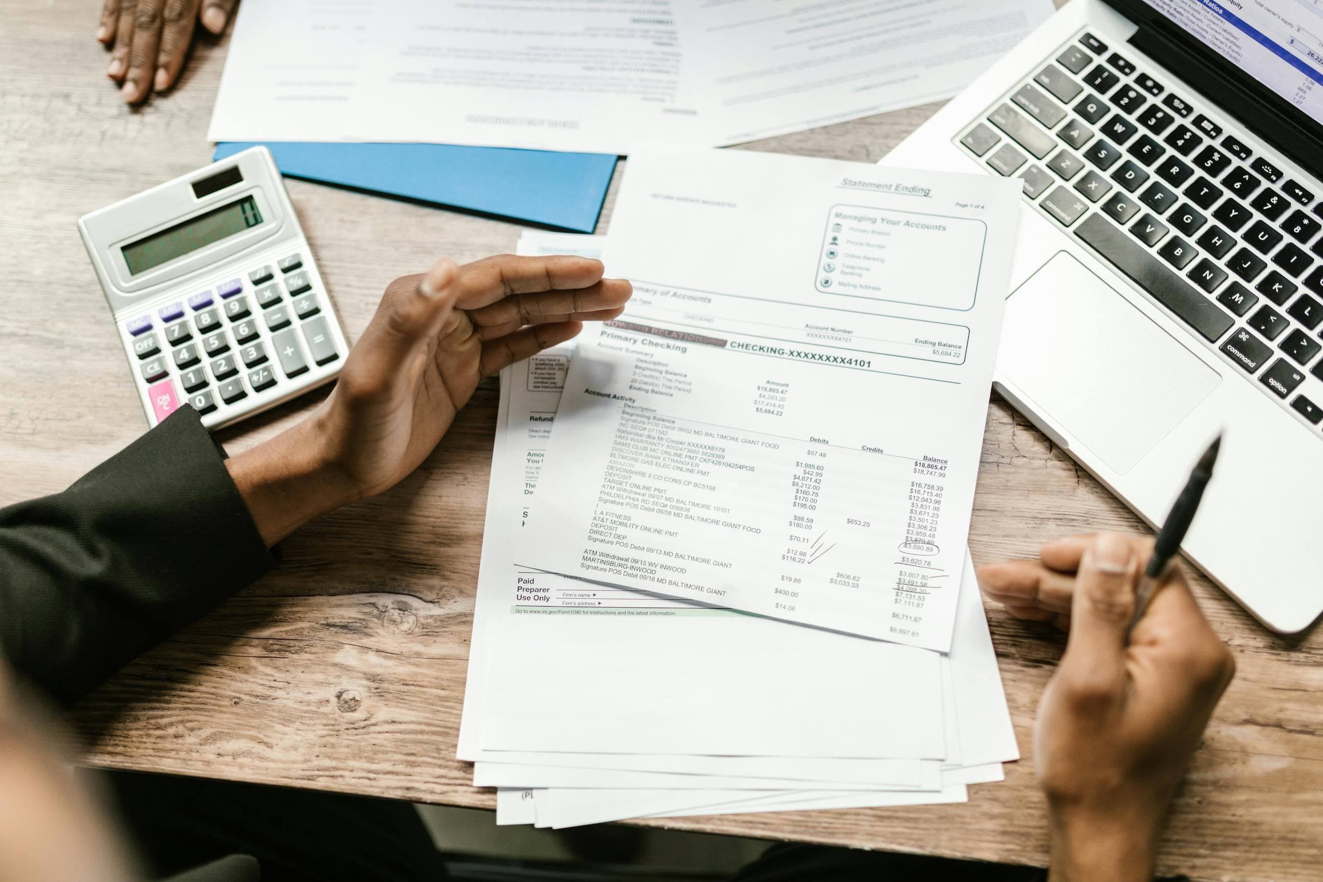 Hands reviewing financial documents with a calculator and laptop – budgeting data annotation pricing for an enterprise AI project